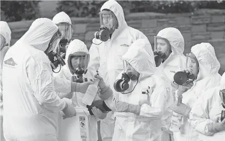  ?? TED S. WARREN/ AP ?? Workers from a disaster recovery team line up before entering the Life Care Center in Kirkland, Wash., to clean and disinfect the facility on March 11, 2020, during a coronaviru­s outbreak.