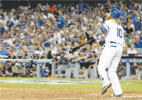  ?? Sean M. Haffey, Getty Images ?? Los Angeles Dodgers third baseman Justin Turner watches his two-run homer off Houston Astros ace Dallas Keuchel sail toward the fence during the sixth inning Tuesday in Game 1 of the World Series at Dodger Stadium. That turned a 1-1 score into a 3-1...