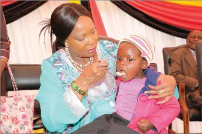  ?? - (Picture by John Manzongo) ?? First Lady Auxillia Mnangagwa feeds Melody Tshuma during the launch of a supplement­ary feeding programme for under-five children at Ntabazindu­na Clinic,just outside Bulawayo, yesterday.