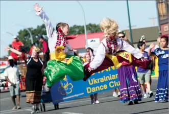  ?? Herald photo by Ian Martens ?? Fawkes Bruinsma and Wyatt Blackburn, from the Troyanda Ukrainian Dance Club, leap above the road as they make their way along the parade route Tuesday during the kickoff for Whoop-Up Days. @IMartensHe­rald