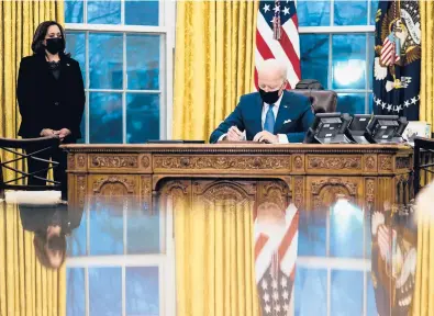  ?? DOUG MILLS/THE NEW YORK TIMES ?? President Joe Biden signs several executive orders directing immigratio­n actions for his administra­tion as Vice President Kamala Harris looks on Tuesday in the Oval Office at the White House.