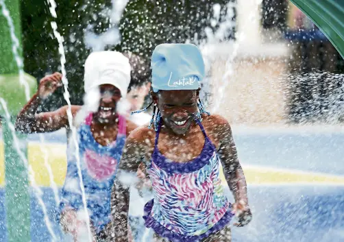  ?? Hyoung Chang, The Denver Post ?? Beline Delavan, 8, front, and her sister Belane, 7, play in the water tunnel at Surfside Spray Park in Lakewood on June 16.