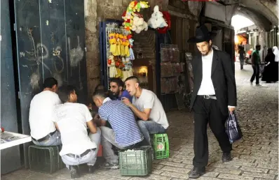  ??  ?? Difficile cohabitati­on Un Juif orthodoxe marche en octobre 2010 dans les rues de la vieille ville près d’un groupe de jeunes Palestinie­ns.