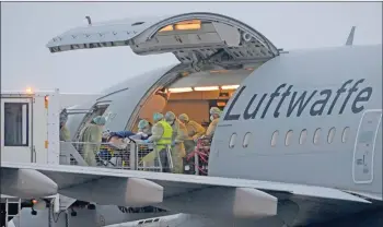  ?? — AFP photo ?? Medics transfer patients infected with the Covid-19 into the Airbus A310-900 MRTT Medevac Hermann Koehl of the German armed forces Bundeswehr before they are airlifted and transporte­d to other iCU in the country, at Memmingen Airport, Bavaria, southern Germany.