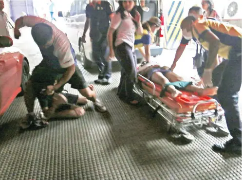  ?? SUNSTAR FOTO / ALEX BADAYOS ?? TRAGEDY. As Jonah Villarin is being boarded into an ambulance after she leapt from the seventh floor of her school, her father punches her boyfriend. This happened 4 p.m. yesterday.