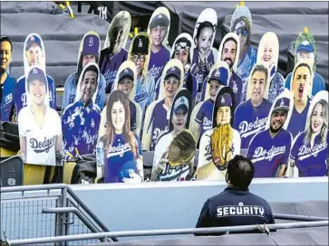  ?? Robert Gauthier Los Angeles Times ?? A SECURITY GUARD stands by cutout photos of fans placed at field level of Dodger Stadium as the Dodgers beat Arizona 9-2 in an exhibition. Cody Bellinger hit a grand slam, and Kenley Jansen threw a scoreless ninth.