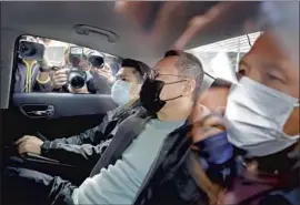  ?? Apple Daily ?? LEGAL SCHOLAR Benny Tai, center, sits in a car after being arrested on Jan. 6. He was among dozens of pro-democracy figures seized in Hong Kong.