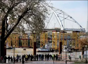  ?? Arkansas Democrat-Gazette/STEPHEN B. THORNTON ?? A crowd watches from the North Little Rock side of the Arkansas River on Friday as the second and final arch for the new Broadway Bridge is floated into place.