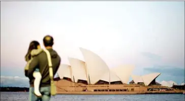  ?? SAEED KHAN/AFP ?? A tourist holds his daughter in front of Sydney’s iconic landmark Opera House on August 25, 2015.