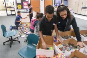  ?? ERIC BONZAR — THE MORNING JOURNAL ?? Garfield Elementary School fifth graders and Student Council members Alex Christian, 11, and Jordana Torres, 10, package canned goods and nonperisha­ble food items Dec. 13, that were collected for classmates in need.