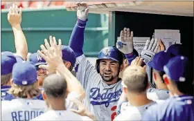  ??  ?? The Dodgers’ Adrian Gonzalez, center, celebrates in the dugout after hitting a solo home run off Reds relief pitcher Jumbo Diaz in the fifth inning Monday in Cincinnati.