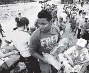  ?? AP ?? Un joven recibe agua y alimentos por parte de los equipos humanitari­os.