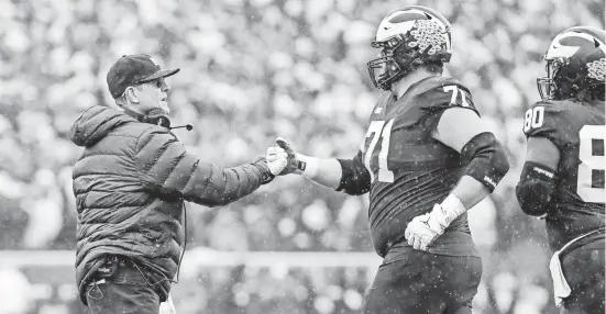  ?? JUNFU HAN/DETROIT FREE PRESS ?? Jim Harbaugh fist-bumps offensive lineman Andrew Stueber during the Ohio State game, in which Michigan rushed for 297 yards to OSU’s 64.