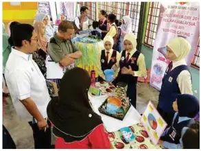  ??  ?? The winning team from SK Dato Demang Hussin explaining their “Gayung” sculpture to the judges.