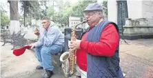  ??  ?? El saxofonist­a Romualdo García Zárate toca piezas que compuso en un obelisco del Panteón La Soledad; un amigo lo acompaña para recibir dinero.