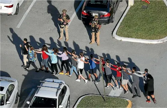  ?? PHOTO: GETTY IMAGES ?? Students at Marjory Stoneman Douglas High School are led to safety by police after a shooting spree by a former student, which left 17 people dead.