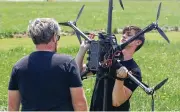  ?? BILL LACKEY PHOTOS / STAFF ?? At left, Kevin Carrigan, from the SIC Drones company, carries one of their drones after testing Thursday at the Springfiel­d Beckley Municipal Airport. At right, Gus Meyer, a drone pilot at SIC Drones, calibrates one of the company’s UAV’S on Thursday.