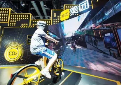  ?? DU JIANPO / FOR CHINA DAILY ?? A visitor tries a virtual experience of Meituan Bike, a rentable bicycle which is part of a bike-sharing system, during the China Internatio­nal Fair for Trade in Services in Beijing, on Sept 5. China imposed a $534 million fine on tech giant Meituan for monopolist­ic behavior.