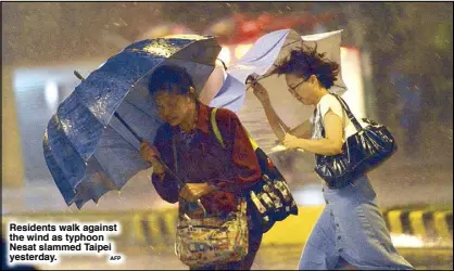  ?? AFP ?? Residents walk against the wind as typhoon Nesat slammed Taipei yesterday.