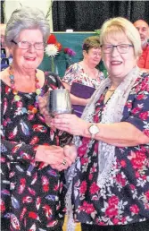  ??  ?? Flower power Marjorie Gibb receives the cup for her floral art from Mairi Philp