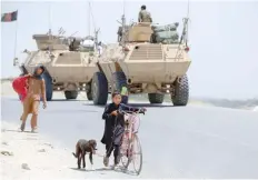  ?? — AFP ?? Afghan children walk past security force personnel as they leave a village during an operation against IS militants in the Chaparhar district.