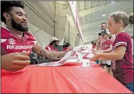  ?? NWA Democrat-Gazette/J.T. WAMPLER ?? Brooklyn Quinn, 7, receives an autograph from Arkansas wide receiver Jared Cornelius on Saturday during the Razorbacks’ annual Fan Day at the University of Arkansas, Fayettevil­le. Football players and coaches as well as the soccer and volleyball teams...