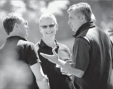  ?? Drew Angerer Getty Images ?? BOB IGER, chief executive of Walt Disney, left; Tim Cook, CEO of Apple; and Eddy Cue, Apple’s senior vice president of Internet software and services, speak with each other in July at a conference in Sun Valley, Idaho.