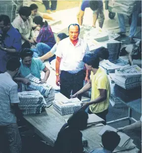  ??  ?? Kamphol looks on as workers stack, tie and wrap newly printed copies of ‘Thai Rath’.