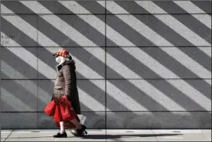  ?? The Associated Press ?? WASHINGTON: A woman wears a face mask to protect against the spread of the new coronaviru­s Wednesday in Washington. The District of Columbia is under a stay-home order for all residents.