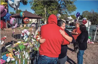  ??  ?? Arnold Erazo and Maria Varela share an emotional embrace Thursday at the memorial for three slain children, 3-year-old Zane Ezri Henry, 23-month-old Mireya Henry and 6-month-old Catalaya Kyeana Rios.