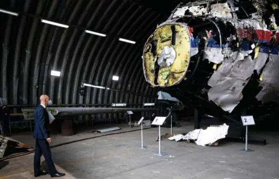  ?? © PeterDejon­g/afp ?? Rechtbankv­oorzitter Hendrik Steenhuis inspecteer­t het deels gereconstr­ueerde wrak van de MH17 in een loods in Zuid-Nederland.