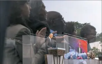  ?? Zach Gibson/AFP/Getty Images ?? Members of the audience are reflected in a buffer panel as Mr. Obama speaks.