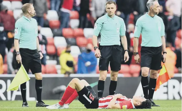  ??  ?? Luke O’Nien is down at the full-time whistle as the match officials look on.