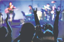  ??  ?? Above: Fans cheer Metallica at the band’s benefit performanc­e for its All Within My Hands foundation at the Masonic in San Francisco. Top: Singer-guitarist James Hetfield (left) and bassist Robert Trujillo lead the acoustic set, which also featured several backing musicians.