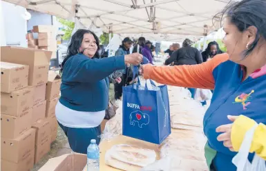  ?? JOSHUA BESSEX/AP ?? Yvonne King, left, hands out food to community members Tuesday near a Tops Friendly Market in Buffalo, New York.