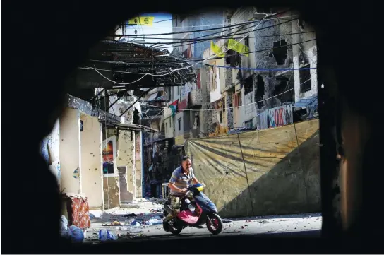  ??  ?? A man rides on a motorbike inside a refugee camp near Sidon in southern Lebanon. The country needs billions of dollars in funds to help rebuild wardamaged and negelcted infrastruc­ture. (Reuters)