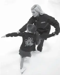  ??  ?? below Katy Taylor helps Olivia Henry skate backwards in a circle during a coaching session on Monday in Houston.