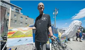  ??  ?? Varouj Mouralian, a resident of the Main Street tent city, shows off a painting he created at the site from which he is being evicted.