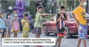  ??  ?? Children try to maintain social distancing rules in Klong Toey slum, Bangkok, Thailand