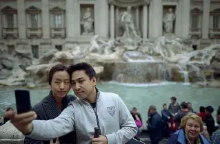  ?? (foto Getty Images) ?? Foto ricordo Due turisti asiatici immortalan­o con un selfie la magnificen­za di Fontana di Trevi, uno dei luoghi simbolo della Capitale, durante la loro vacanza