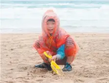  ??  ?? Billy Yao from China enjoys playing on the beach despite the rain.