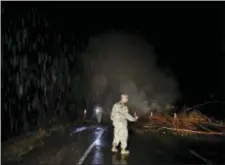  ?? JAE C. HONG — THE ASSOCIATED PRESS ?? First Lt. Aaron Hew Len, center, and Sgt. 1st Class Carl Satterwait­e, of the U.S. National Guard, test air quality near cracks emitting volcanic gases from a lava flow in the Leilani Estates subdivisio­n near Pahoa, Hawaii Thursday. Kilauea has...