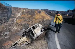  ?? The New York Times/STUART PALLEY ?? Firefighte­rs check a burned-out vehicle Wednesday on the side of Mulholland Highway near Malibu, Calif. The fire that swept through the area west of Los Angeles has charred more than 97,000 acres.