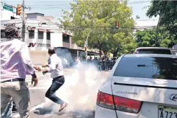  ?? ?? Miembros del PLD próximo a gases lacrimógen­os lanzados por la policía.