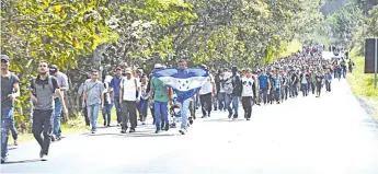  ?? — AFP photo ?? Honduran migrants walk with a Honduran flag near Esquipulas, Chiquimula departamen­t, Guatemala after crossing the border in Agua Caliente from Honduras on their way to the US.