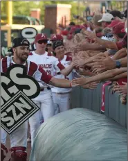  ?? (NWA Democrat-Gazette/J.T. Wampler) ?? Casey Opitz and other Arkansas baseball players celebrate with fans after a victory in 2019 at Baum-Walker Stadium in Fayettevil­le. Officials have not set an official number of fans who will be allowed for games this season, but Arkansas officials said they expect that number to be at least 4,000.