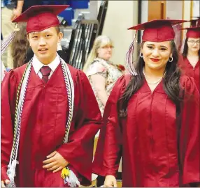  ?? Westside Eagle Observer File Photo/RANDY MOLL ?? Seniors Adam Lee and Isabella Lopez smile as they march in during Gentry High School graduation ceremonies held last year at the Bill George Arena in Siloam Springs.