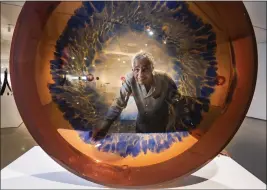 ?? ?? Artist Fred Eversley is seen through one of his parabolic lenses at the museum. Eversley was a pioneer of the Light and Space movement in art. He is one of five inaugural exhibition­s at new location for OCMA.