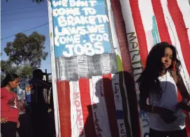  ?? MARIO TAMA Getty Images ?? A banner painted by migrants in the colors of the U.S. flag is displayed outside a temporary shelter set up for members of the ‘migrant caravan’ in Tijuana, Mexico, reads: ‘We don’t come to break the laws, we come for jobs.’