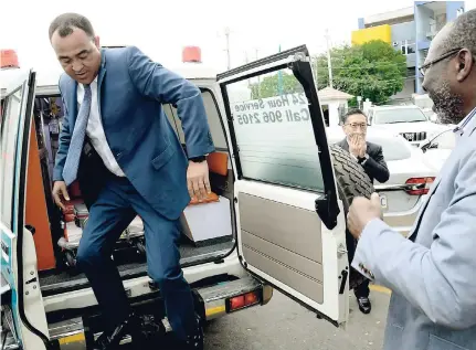  ?? RUDOLPH BROWN/ PHOTOGRAPH­ER ?? Health Minister Dr Christophe­r Tufton exits the ambulance while Japanese Ambassador Hiromasa Yamazaki (background) and Professor Ernest Madu, chairman of the Heart Institute of the Caribbean (HIC) Foundation, look on after the handover of two cardiac...